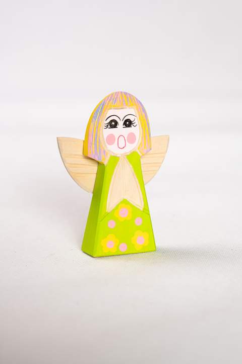 Drewniany anioł, duży, z zielonym tułowiem w żółte kwiaty z różowymi środkami, włosy w kolorze żółtym fioletowym i różowym