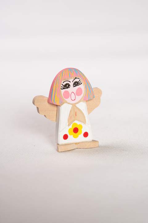 Anioł z drewna, mały, z białym tułowiem z żółtym kwiatkiem z czerwonymi kropkami,włosy w kolorze różowym niebieskim i żółtym