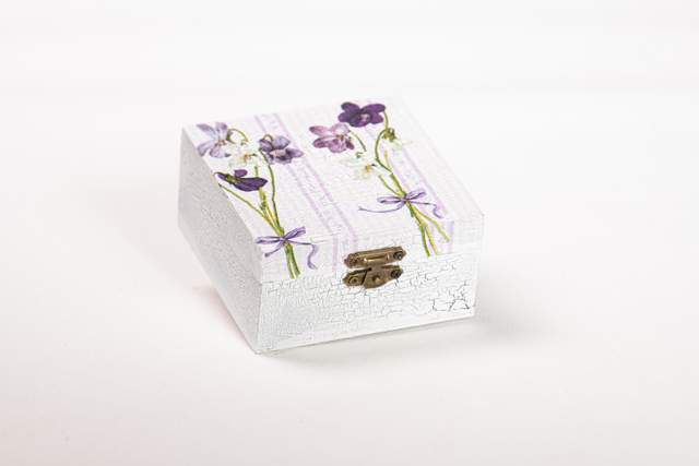 Szkatułka kwadratowa z drewna, mała, szara, z dwiema wiązankami bratków w kolorze jasnego fioletu na długich, zielonych gałązkach