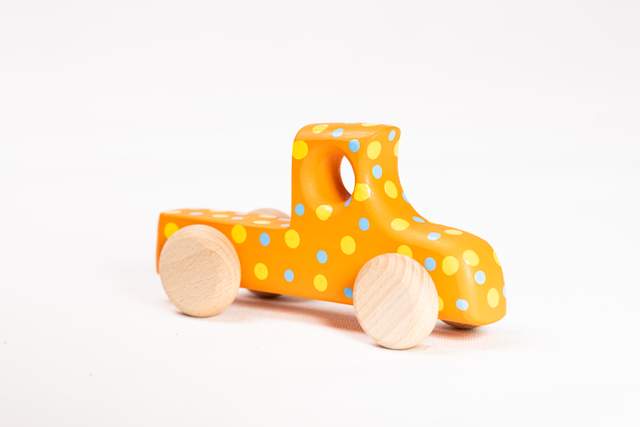 Drewniany samochód zabawka, mały, pomarańczowy w kropki niebieskie i żółte, z małym okienkiem