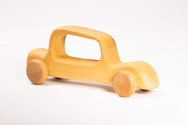 Drewniany samochód zabawka, duży, jasno-brązowy, z dużym, podłużnym oknem